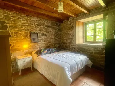 a bedroom with a bed in a stone wall at Refugio del Camino in Albá
