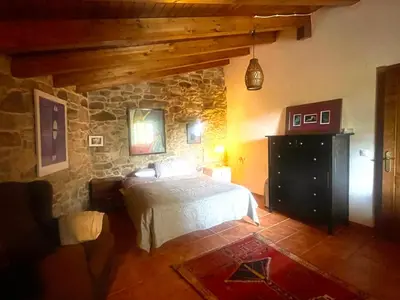 a bedroom with a bed and a stone wall at Refugio del Camino in Albá