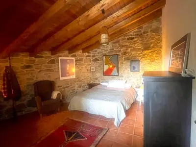 a bedroom with a bed and a stone wall at Refugio del Camino in Albá