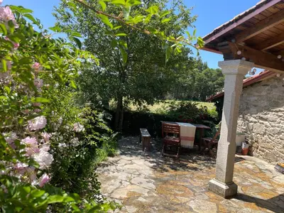 a patio with a table and chairs in a garden at Refugio del Camino in Albá