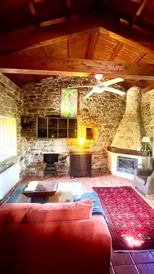 a living room with a red couch and a stone wall at Refugio del Camino in Albá