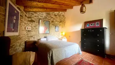 a bedroom with a bed and a stone wall at Refugio del Camino in Albá