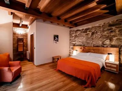 a bedroom with a bed and a stone wall at Aldea Rural Pazos De Arenteiro in Pazos de Arenteiro