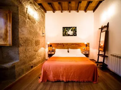 a bedroom with a bed with an orange blanket at Aldea Rural Pazos De Arenteiro in Pazos de Arenteiro