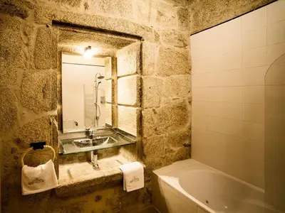 a stone bathroom with a sink and a bath tub at Aldea Rural Pazos De Arenteiro in Pazos de Arenteiro