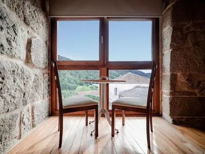 a table and two chairs in a room with a window at Aldea Rural Pazos De Arenteiro in Pazos de Arenteiro