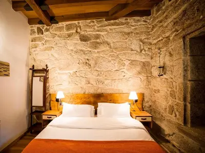 a bedroom with a large bed in a stone wall at Aldea Rural Pazos De Arenteiro in Pazos de Arenteiro
