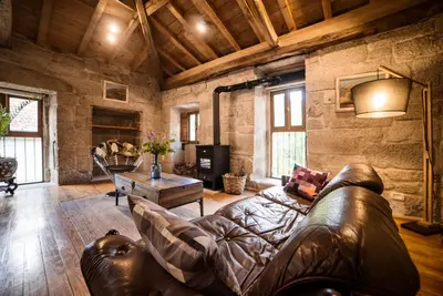 a living room with a leather couch and a table at Aldea Rural Pazos De Arenteiro in Pazos de Arenteiro