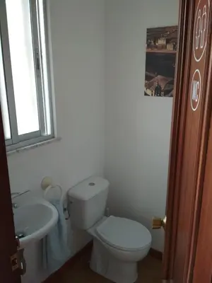 a white bathroom with a toilet and a sink at Casa Do Marabillas in Portomarin