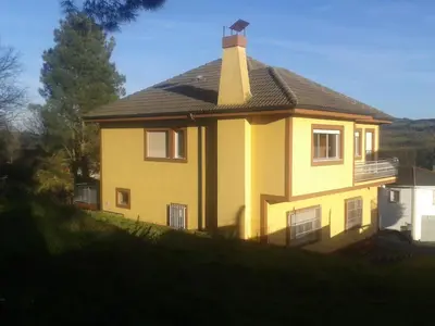 a yellow house with a roof on a hill at Casa Do Marabillas in Portomarin