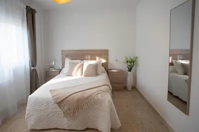 a bedroom with a large white bed with a mirror at Apartamento Río Sol in Sarria