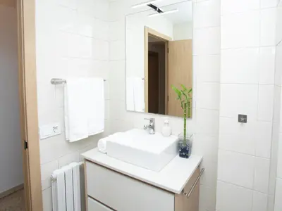 a white bathroom with a sink and a mirror at Apartamento Río Sol in Sarria