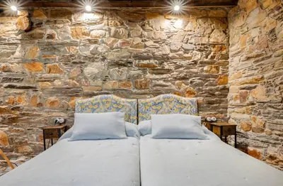 a stone walled bedroom with a bed and two pillows at VUT La casita del Pajar in Vega de Espinareda