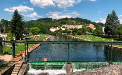 a bridge over a river with people in a park at VUT La casita del Pajar in Vega de Espinareda