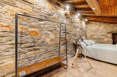 a bedroom with a stone wall with a bed and a tripod at VUT La casita del Pajar in Vega de Espinareda