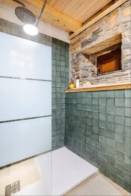 a glass shower in a bathroom with a stone wall at VUT La casita del Pajar in Vega de Espinareda