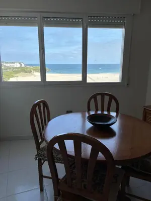 a dining room table and chairs with a view of the beach at En Foz en 1a línea de playa in Foz