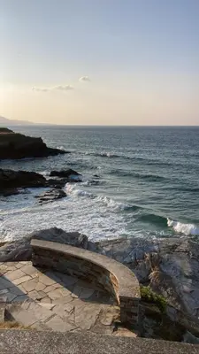 a bench sitting on the rocks near the ocean at En Foz en 1a línea de playa in Foz