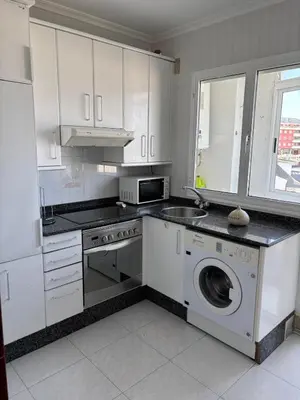 a white kitchen with a washing machine and a sink at En Foz en 1a línea de playa in Foz