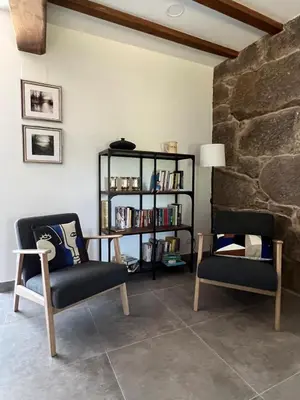 a living room with two chairs and a book shelf at A CASIÑA dos LARANXOS in Cenlle