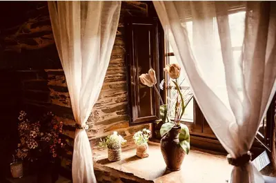 a window with curtains and flowers on a window sill at Casa Da Fragua in Samos