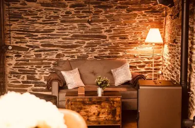 a living room with a couch and a stone wall at Casa Da Fragua in Samos