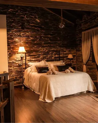 a bedroom with a bed and a stone wall at Casa Da Fragua in Samos