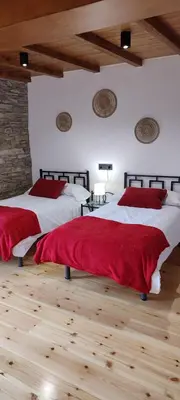 two beds with red pillows in a bedroom with wooden floors at Costa A Mariña in Barreiros