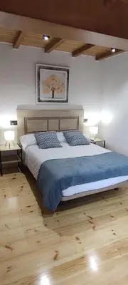 a bedroom with a large bed with blue sheets and wooden floors at Costa A Mariña in Barreiros