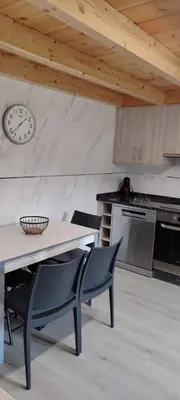 a kitchen with a table and chairs and a clock on the wall at Costa A Mariña in Barreiros