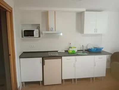 a kitchen with white cabinets and a black counter top at Xulia in Viavélez