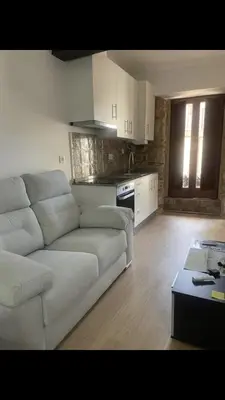 a living room with a white couch and a kitchen at CASA CRISTINA Alojamiento céntrico en pleno casco histórico y centro de la ciudad in Monforte de Lemos