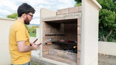 a man standing in front of an outdoor oven at Xeocámping Montañas do Courel