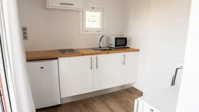a small kitchen with white cabinets and a microwave at Xeocámping Montañas do Courel