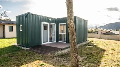 a green tiny house with a wooden deck at Xeocámping Montañas do Courel