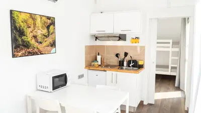 a white kitchen with a table and a microwave at Xeocámping Montañas do Courel