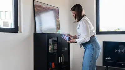 a woman standing in front of a tv holding a remote control at Xeocámping Montañas do Courel