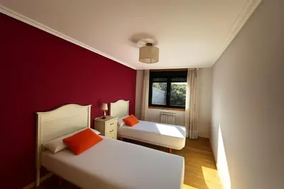 a bedroom with two beds and a red wall at Ribeira Sacra Suites in Nogueira de Ramuin