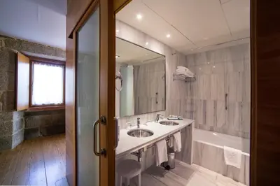 a bathroom with a sink and a tub and a mirror at Parador de Santo Estevo in Santo Estevo de Rivas de Sil