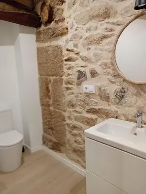 a bathroom with a white sink and a stone wall at Duplex en Ribeira Sacra in Sistín