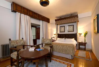 a hotel room with a bed and a table and chairs at Parador de Santiago - Hostal Reis Catolicos in Santiago de Compostela