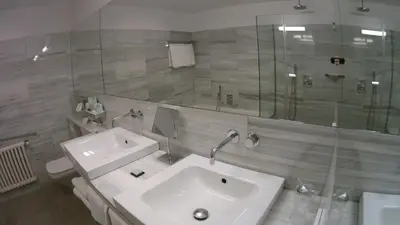 a bathroom with a sink and a glass shower at Parador de Santiago - Hostal Reis Catolicos in Santiago de Compostela