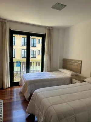 a hotel room with two beds and a large window at Piso Ría de Ribadeo in Ribadeo