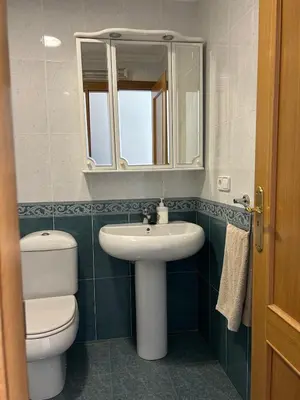 a bathroom with a sink and a toilet and a mirror at Piso Ría de Ribadeo in Ribadeo