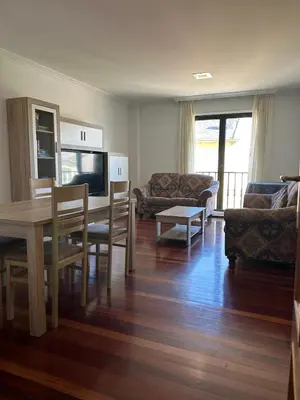 a living room with a table and chairs and a television at Piso Ría de Ribadeo in Ribadeo