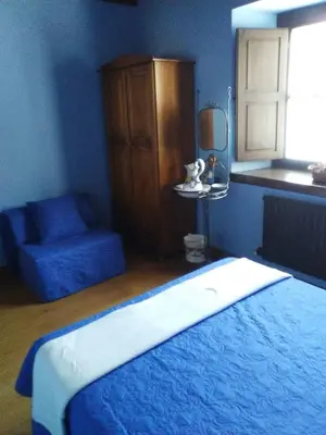 a blue bedroom with a bed and a chair at Hospedaje - Ferrería Quintá in Quiroga