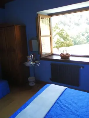 a bedroom with a large window and a bed with a blue blanket at Hospedaje - Ferrería Quintá in Quiroga