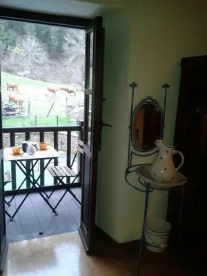 a room with a balcony with a table and a mirror at Hospedaje - Ferrería Quintá in Quiroga