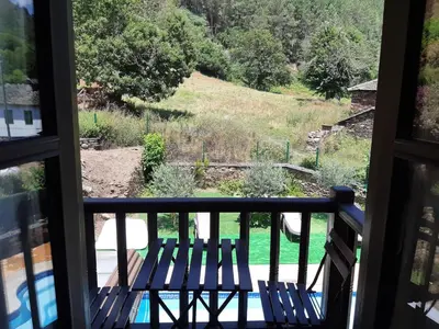a view from the balcony of a house with two benches at Hospedaje - Ferrería Quintá in Quiroga