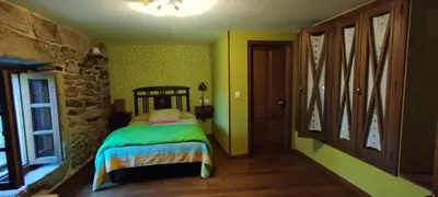 a bedroom with a bed and a stone wall at Casa mañoso in Cea